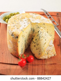 Wheel Of Blue Cheese And Bowl Of Olives On Cutting Board