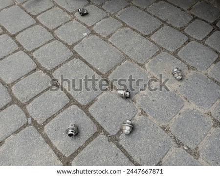 Wheel bolts lie on the cobblestones. The bolts fixing the car wheel are unscrewed and lying on the platform.