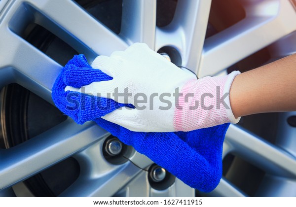 Wheel car cleaning and polished at alloy surface\
with blue microfiber or microfibre towel. Including with glove and\
hand. Result in shiny for car detailing, car washing and service\
business concept.