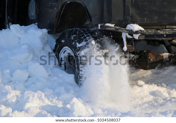  wheel of  car is\
stuck in snow. spray of snow from  rotating wheel of winter tires.\
slipping machine in  snow.  machine is in captivity of snowdrift\
after  snowfall.