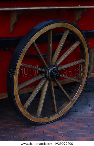 Wheel from\
cart, stroller. Antique trolley wheel made of wood and iron lining,\
Wheel from a modern red\
carriage.