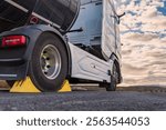 Wheel chocks placed on the drive wheel of a tanker truck to immobilize it for safety during the loading or unloading processes.