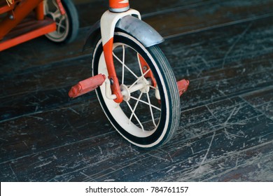 Wheel Of Classic Kids Tricycle With Pedal On Wooden Floor Texture Background.