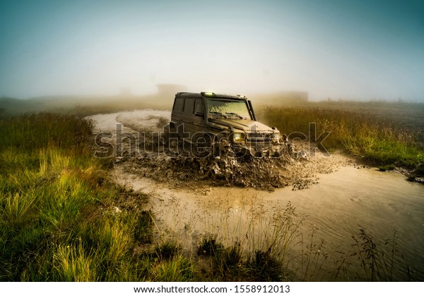 Wheel close up in a countryside landscape\
with a muddy road. Off-road vehicle stuck on impenetrable road\
after rain in the\
countryside