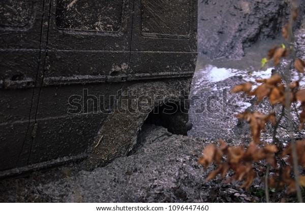 Wheel in deep\
puddle of mud. Dangerous expedition concept. Offroad tire covered\
with mud on nature background. Fragment of car stuck in dirt and\
overcomes obstacles, close\
up.