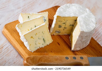 Wheel Of Delicate Blue Cheese With Cut Slices On Wooden Cutting Board..