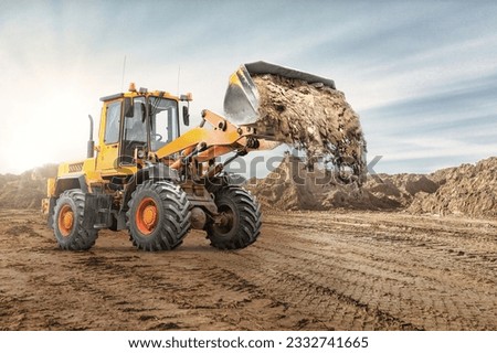 Wheel front loader bulldozer pours sand. Distributes sand for road construction. Powerful earthmoving equipment. Construction site. Rental of construction equipment