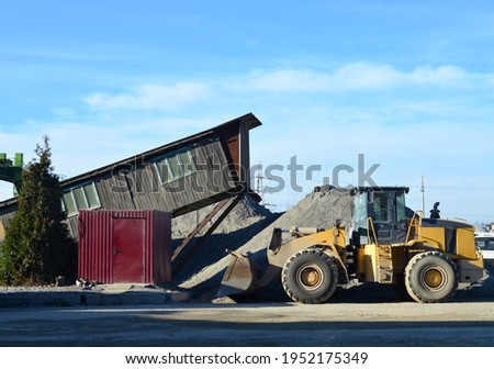 Wheel loader at construction site. Fron-end loader unloads crushed stone and unloading bulk cargo from gravel pit. Gravel  a cement production site. Stockfoto © 