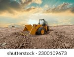Wheel loader are digging the soil in construction site  on sunset background