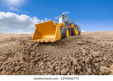 Wheel loader are digging the soil in the construction site with a cloud and blue sky background.