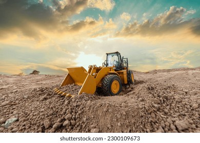 Wheel loader are digging the soil in construction site  on sunset background - Shutterstock ID 2300109673
