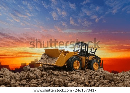 Wheel loader are digging the soil in the construction site on the  sunset background