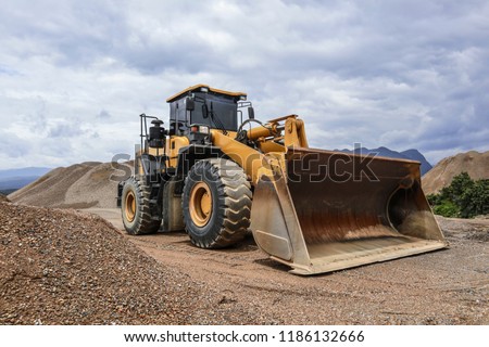 Wheel loader excavator and background of crushed stone hills. Heavy equipment.