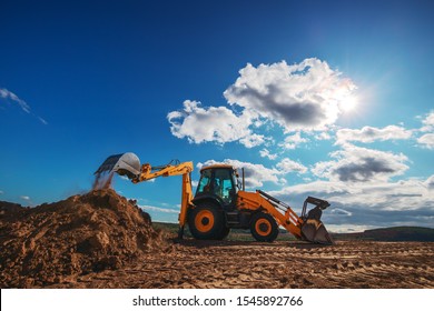 Wheel loader excavator with field background during earthmoving work, construction building