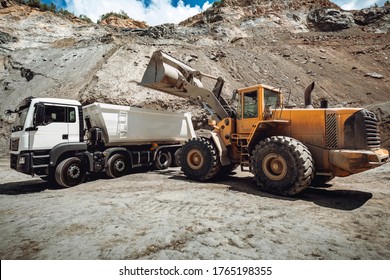  Wheel loader loading gravel and sand into dumper trucks. Machinery and transportation details