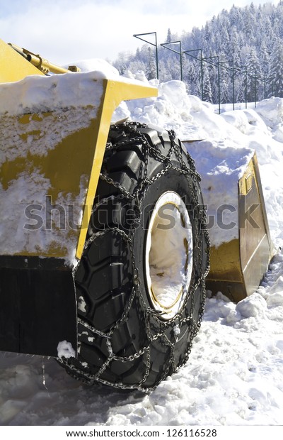 Wheel\
loader machine removing snow in winter on the\
road