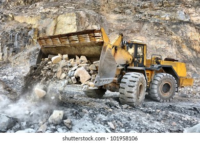Wheel loader machine unloading rocks in the open-mine of iron ore