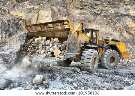 Wheel loader machine unloading rocks in the open-mine of iron ore