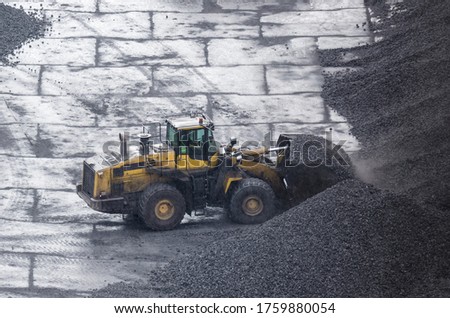 WHEEL LOADER - Machine at work on the yard of a coal storage site in rainy weather

