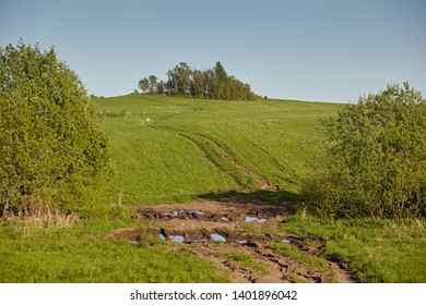 Wheel off-road track in a countryside landscape with a muddy road. Extreme path rural dirt. The spring landscape and traces from the passage of transport on the surface