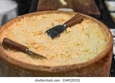 A Wheel Of Parmesan Cheese With Cheese Knives