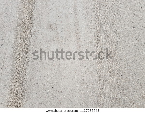 Wheel print mark on wet sand background. Car tyre\
trace on sand view from\
top