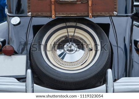 Wheel and suitcase on the trunk of an old car 