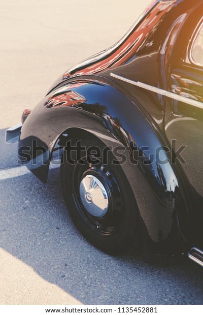 Wheel in a vintage car.\
Detail of rear quarter panel, whitewall tires and chrome hubcap of\
vintage car