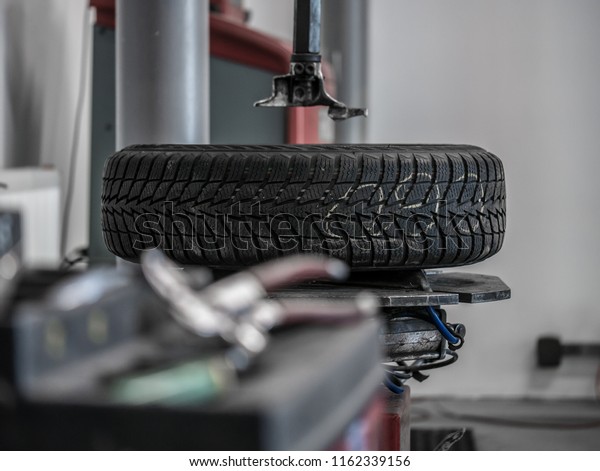 Wheel whit winter tire on tire\
changing machine in a workshop. Wheel on tire changing\
machine.