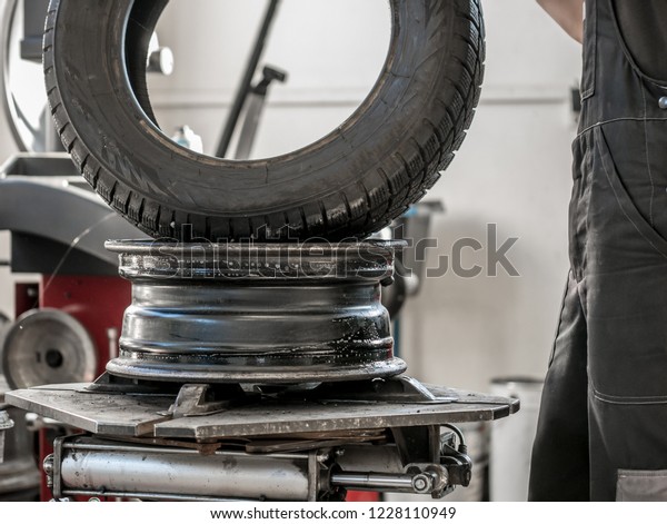 Wheel whit winter tire on tire\
changing machine in a workshop. Wheel on tire changing\
machine.