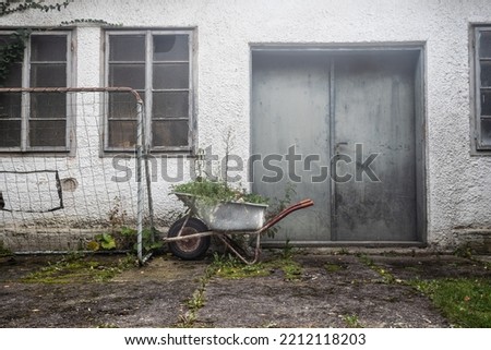 Wheelbarrow behind a garage in City
