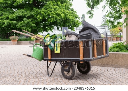 Wheelbarrow of a gardener filled with the gardening tools in the gardens. Gardening concept