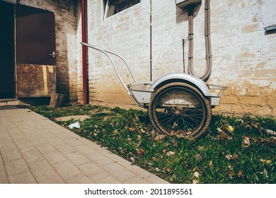 Wheelbarrow on a grass field with an interesting background of an old house . High quality photo