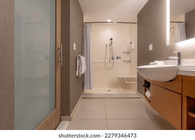 Wheelchair accessible hotel bathroom shower with tile floor and walls.