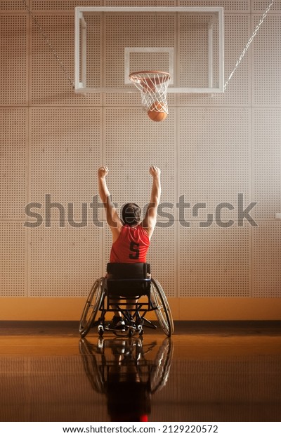 Wheelchair\
Basketball Play: Player Shooting Ball Successfully, Scoring a\
Perfect Goal, Celebrating with Raised Hands. Skill of a Winning\
Person with Disability. Back View\
Shot