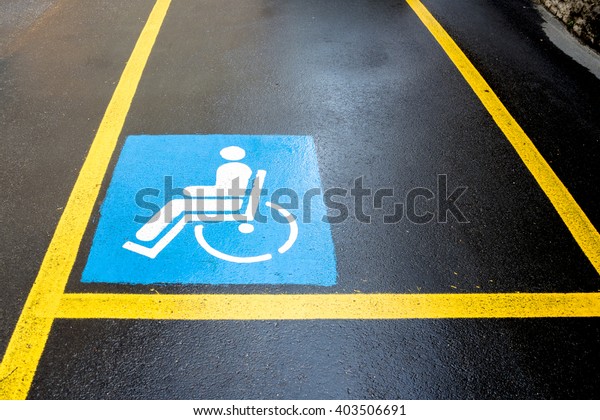 Wheelchair Handicap Sign on dark asphalt\
road street background- handicap parking\
place