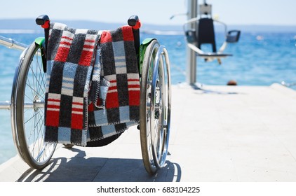 Wheelchair & Lifting Crane On The Beach.Medical Equipment Let Paralyzed & Disabled People Enjoy Summer Vacation At Sea.Specialized Equip Help Injured Handicap People Recover, Rehab From Injury