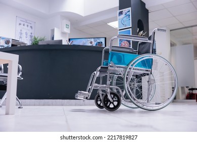 Wheelchair Next To Reception Desk In Family Waiting Area Of Medical Clinic Building. Patient Admission Area At Entrance Of Hospital With Furniture And Medical Equipment.