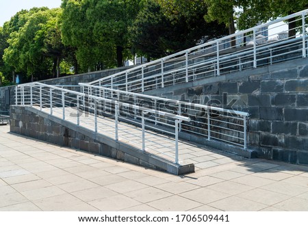 A wheelchair ramp, an inclined plane installed in addition to or instead of stairs, Slope walkway for disabled people, people pushing strollers, carts with stainless bars to prevent falling