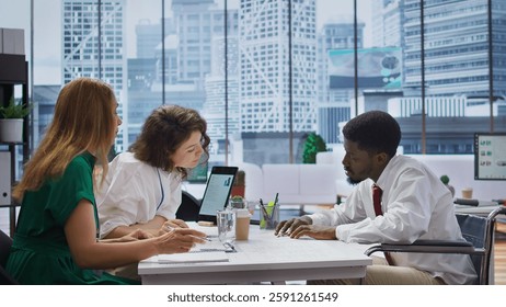 Wheelchair user job seeker fills in application form during interview, discuss with HR team about assistive integration within the company. Disability friendly inclusive adaptive office. Camera B.