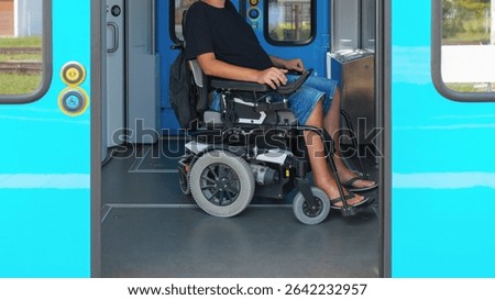 Wheelchair user using accessible train travel waits at the door of a train, showing the spacious interior designed for easy access. The user appears relaxed in casual attire.