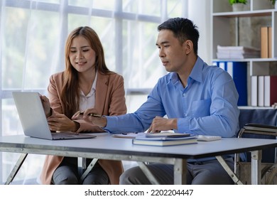 A wheelchair-bound business man and an Asian female accountant have a meeting to discuss finances with graphs and laptop computers. - Shutterstock ID 2202204447