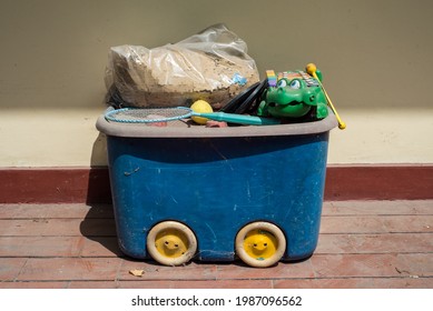 Wheeled Blue Box With Old Dusty Toys On Top. Front View Of Retro Looking Abandoned Toys.