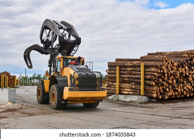 wheeled grapple loader in the timber yard of a woodworking plant