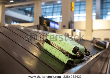 Wheeled suitcase on a luggage belt at the airport terminal.