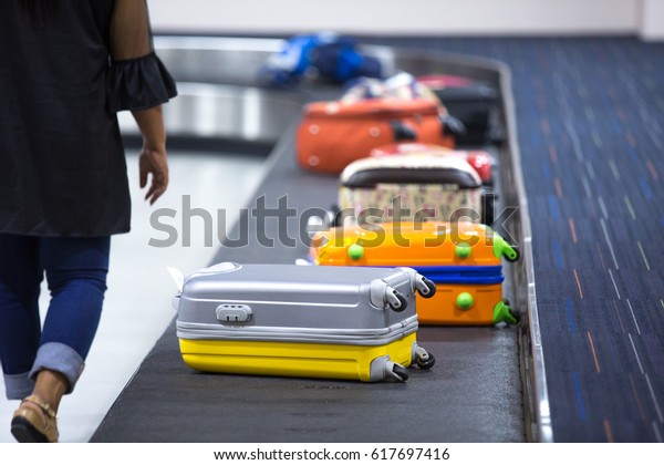 Wheeled suitcase on a luggage belt at the\
airport terminal.