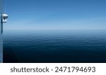 Wheelhouse or Bridge of a ship, viewed from the side. Quiet calm blue sea surface with bow wave. Starboard (right side). Wide image