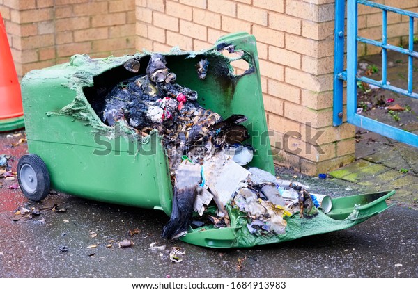 Wheelie bin vandalism on side\
burnt out by fire by vandals in council estate London arson\
attack