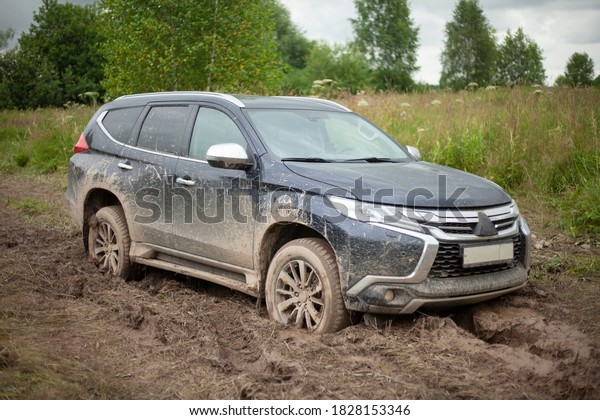 The wheels of the car are stuck in the mud.\
Off-road driving. SUV on a rural road. Waiting for evacuation. The\
black car cannot pass.