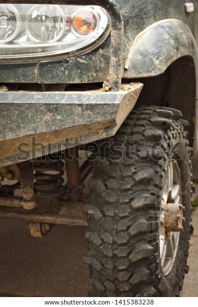 Wheels, lights and bumper are laced in a swamp. Dirty\
truck parts close up.